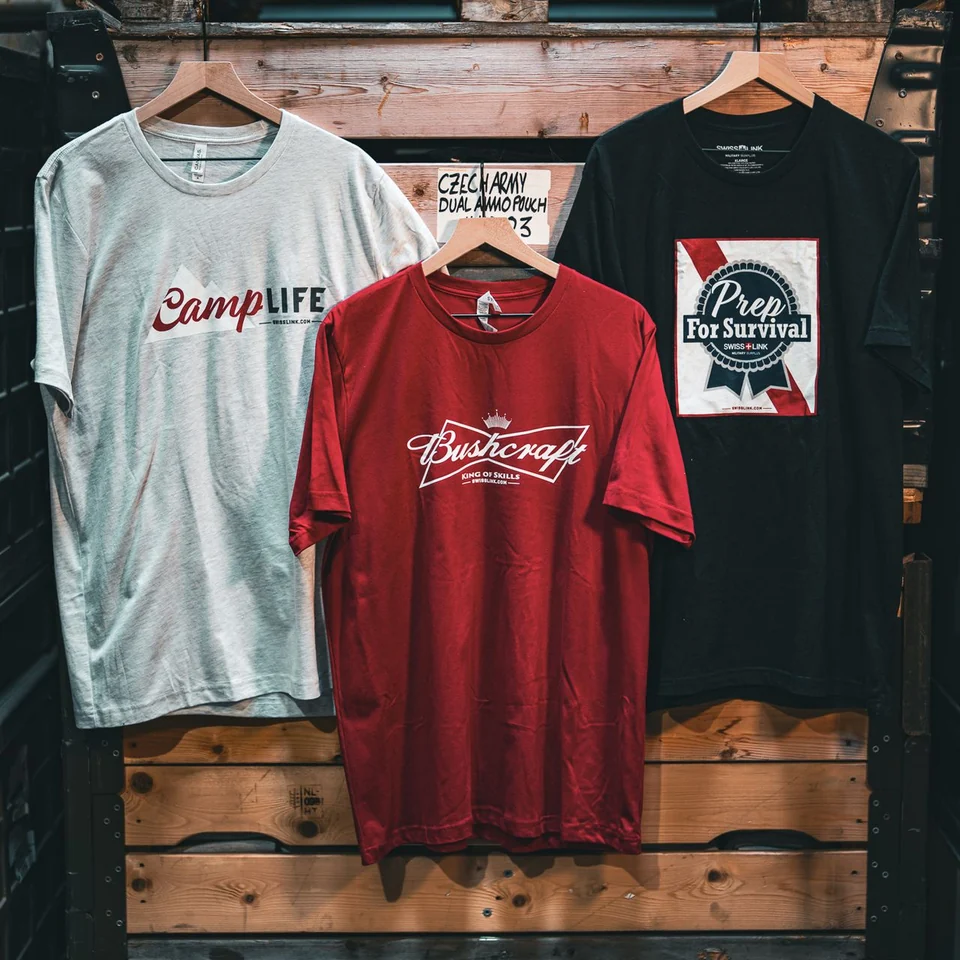 Camp Life in grey, Bushcraft King of Skills in red, and Prep for Survival in black, hanging on wooden crates