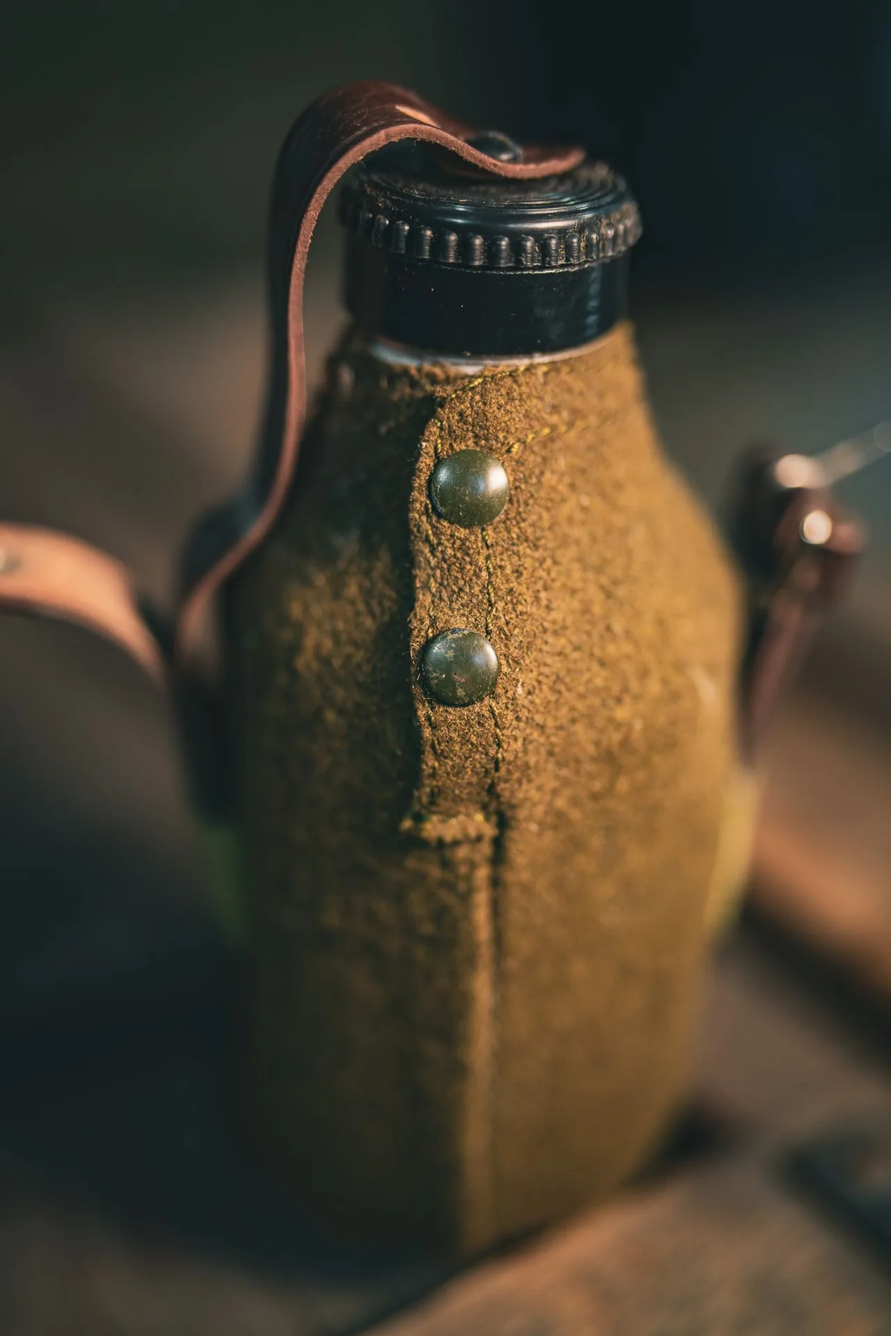 Close view of the olive wool felt cover on the Romanian canteen, with a row of brass snap studs down the back seam