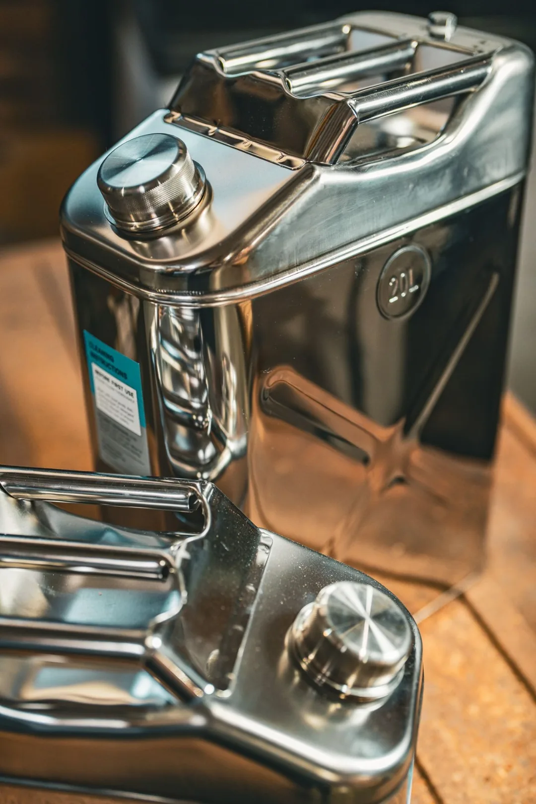 Detail of the knurled screw cap and integrated vent plug on the Swiss Link stainless steel water can, with the cleaning instruction label in view