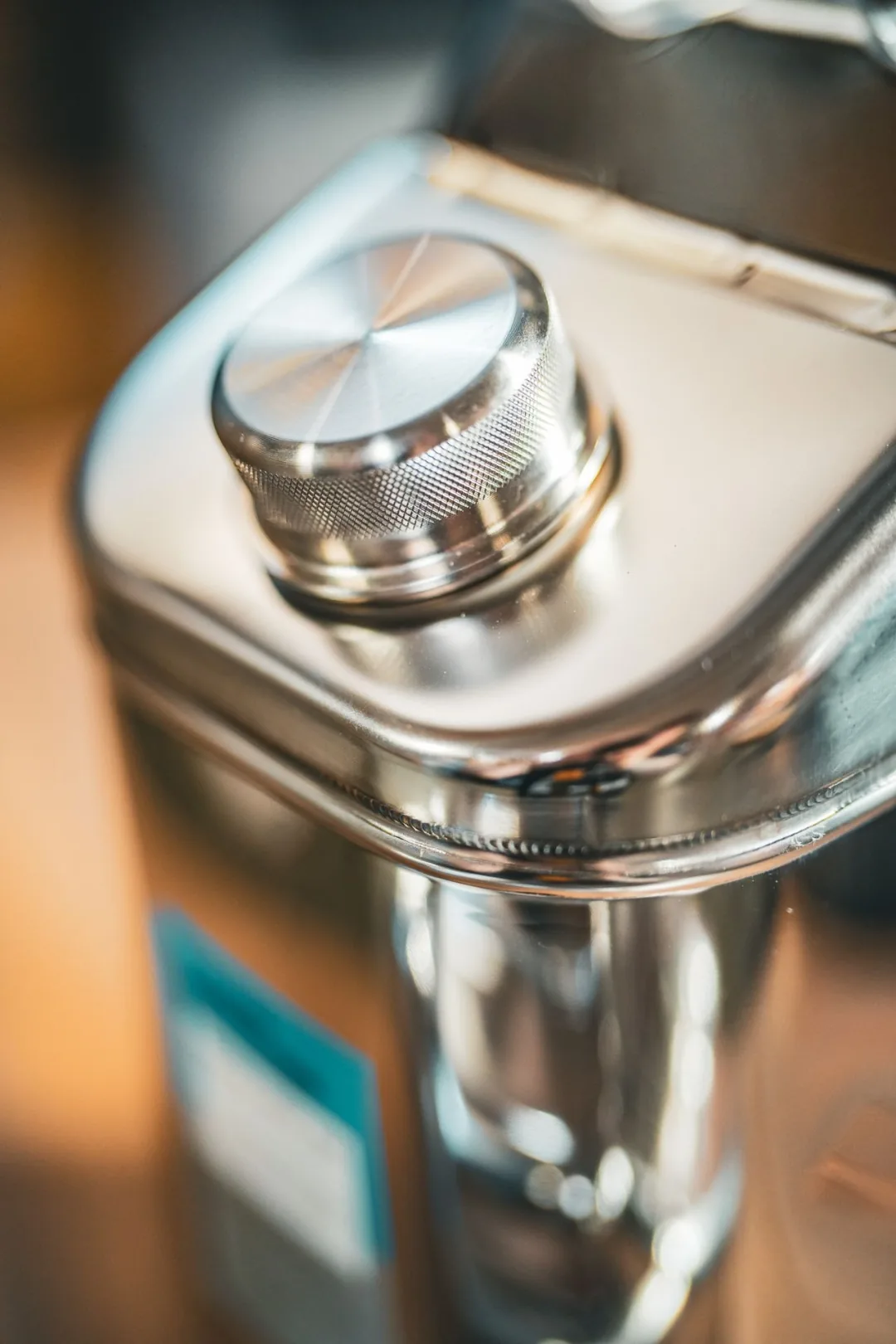 Macro of the knurled stainless steel screw cap on the Swiss Link water can, showing the machined grip pattern and the welded neck seam below