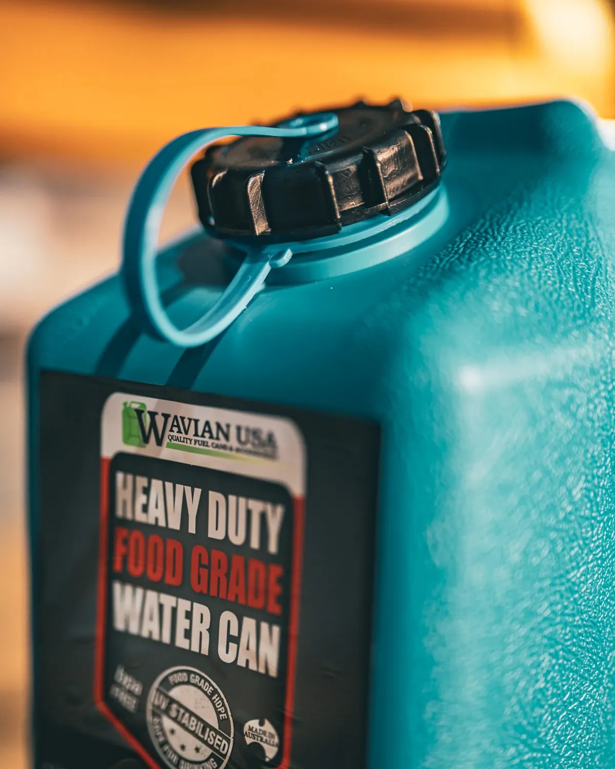 Black screw cap with tether strap on top of the Wavian water can, above the Heavy Duty Food Grade Water Can label