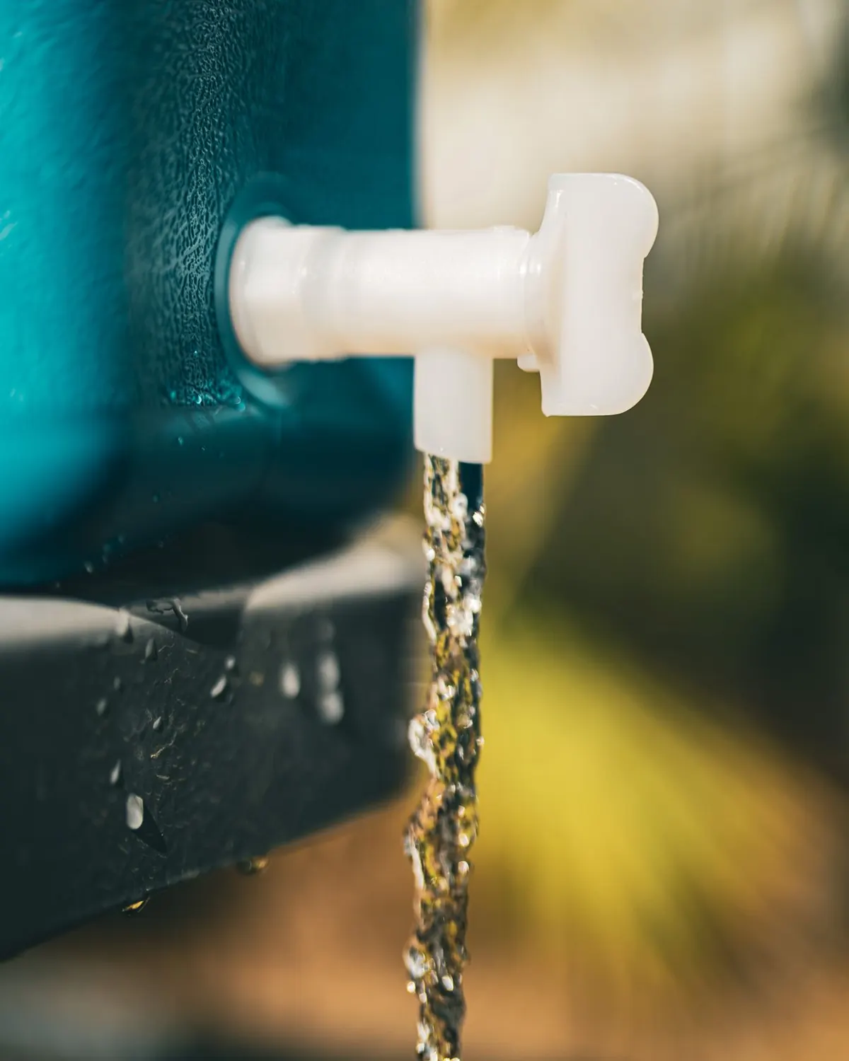 Water pouring from the tap of a Wavian water can standing upright on a tailgate